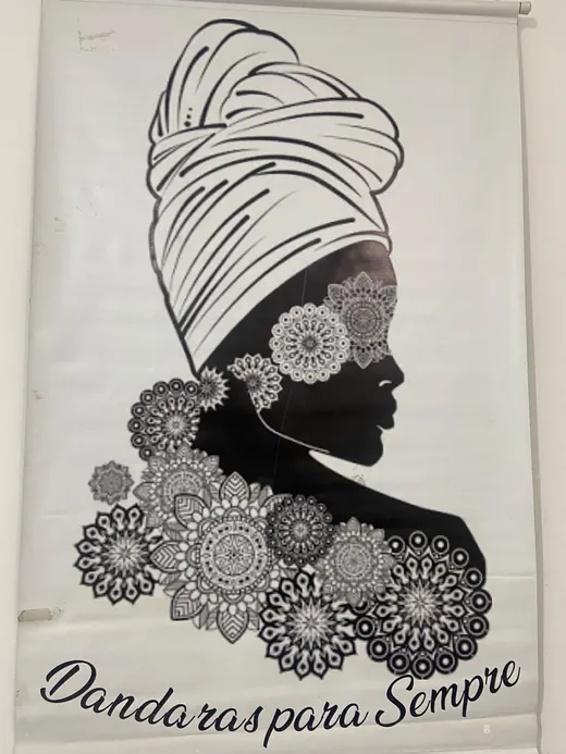 Banner com a ilustração de uma mulher negra de turbante, rodeada de flores, e o nome Dandaras para Sempre