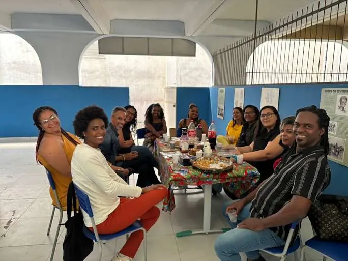 Equipe e participantes reunidos em volta de uma mesa na sede