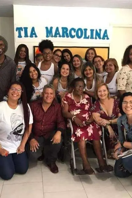 Grupo de mulheres embaixo de uma placa com o nome Tia Marcolina