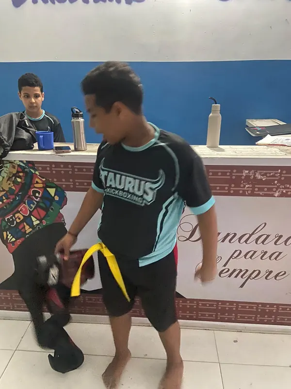 Aluno com a camisa da Equipe Taurus segura a faixa amarela no salão do espaço