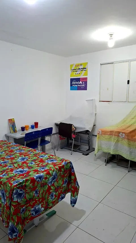 Sala do Salão Social com macas cobertas de tecido estampado, cadeiras e cartazes na parede