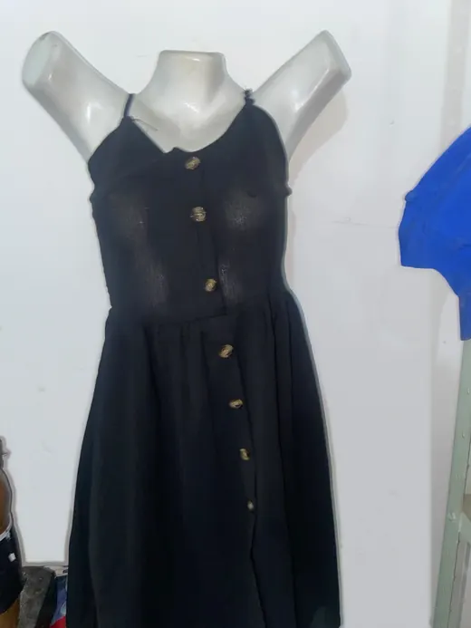 Vestido preto de alças, com botões na frente, num manequim do ateliê